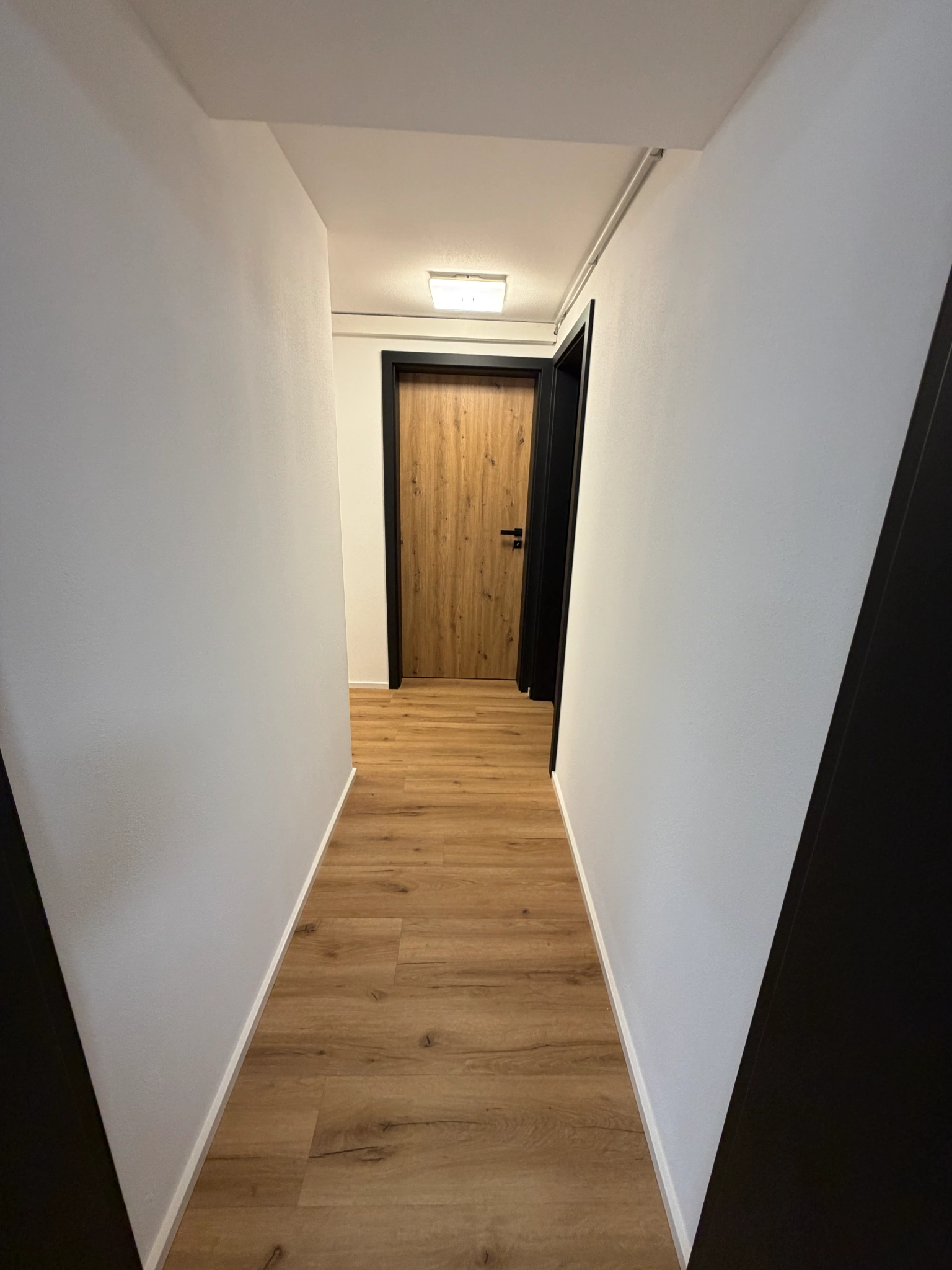 Weiße Wände und Boden in Holzoptik im Flur